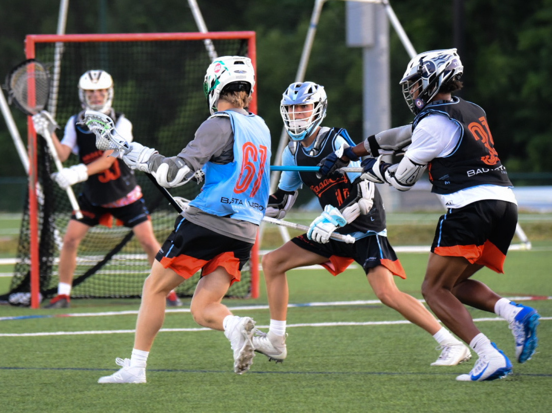 Youth lacrosse players attacking near the crease
